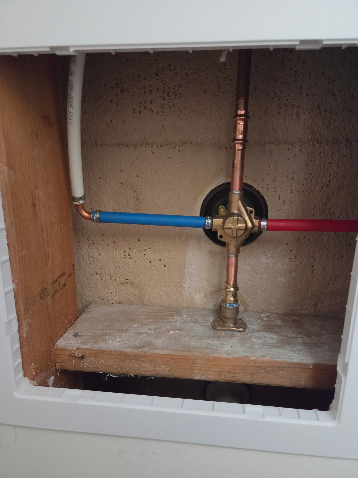 Brass bypass manifold with red and blue PEX supply lines for a whole-house water treatment system.