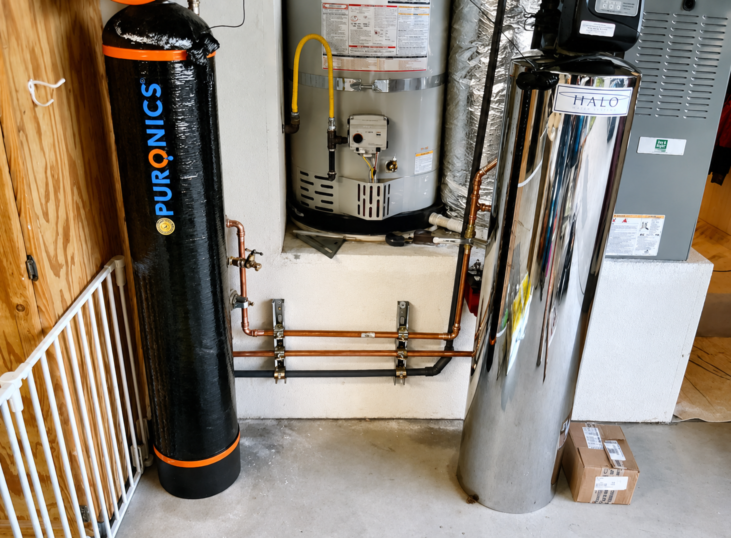 Puronics and Halo whole-house water treatment tanks installed alongside a water heater with copper supply piping.