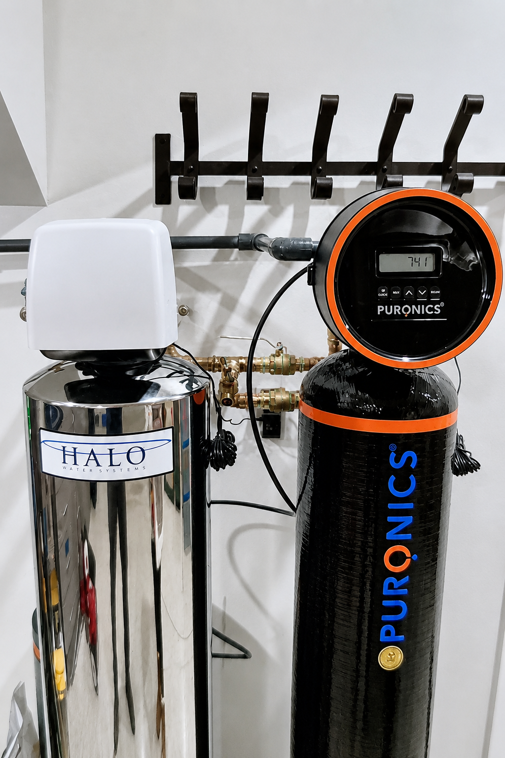 Halo whole-house filtration tank and Puronics treatment tank installed side by side with copper manifold piping.