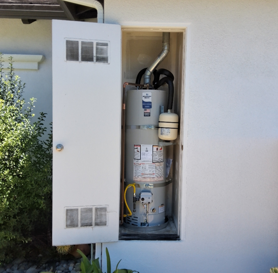Newly installed gas water heater with an expansion tank inside an exterior utility closet.